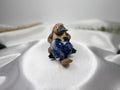 Treasured Energies polished blue Sodalite crystal heart held by a small platypus figurine on white satin fabric