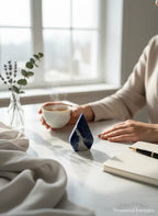 Treasured Energies polished royal blue Sodalite crystal flame crystal sculpture on a desk with a cup of tea and notebook.