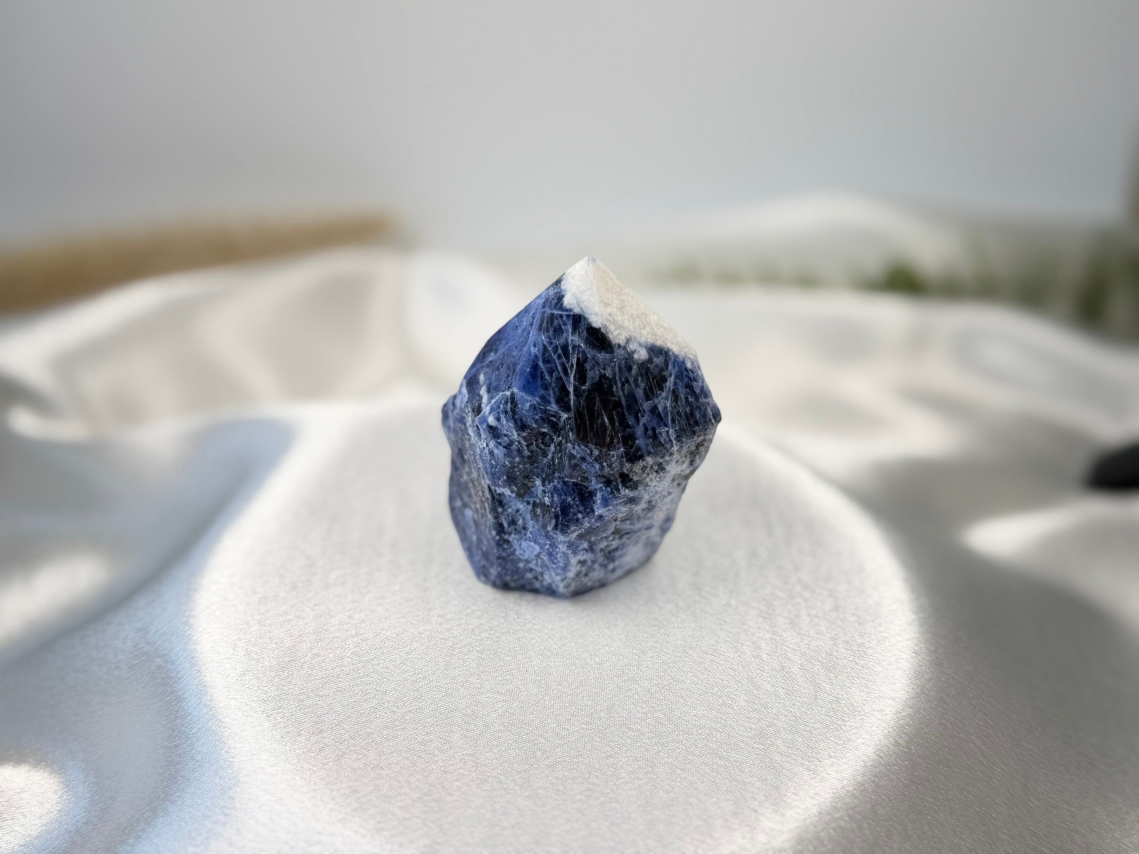 Treasured Energies sodalite crystal point with a raw base and polished top, featuring deep blue and white mineral tones.
