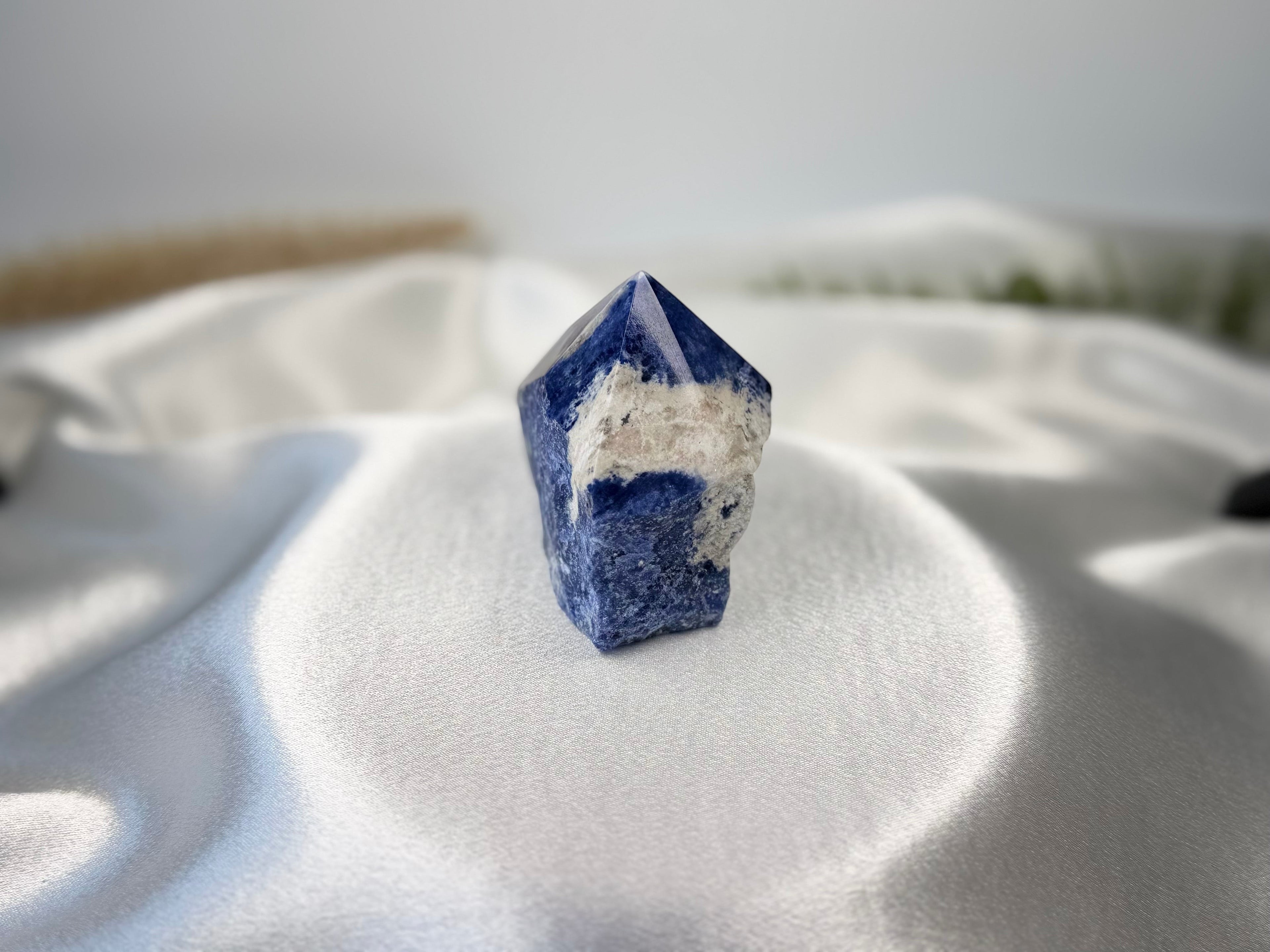 Treasured Energies sodalite crystal tower with a polished point and raw base featuring deep blue and white mineral tones.