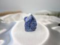 Treasured Energies Sodalite crystal tower with a polished point and raw base on a white satin fabric background.