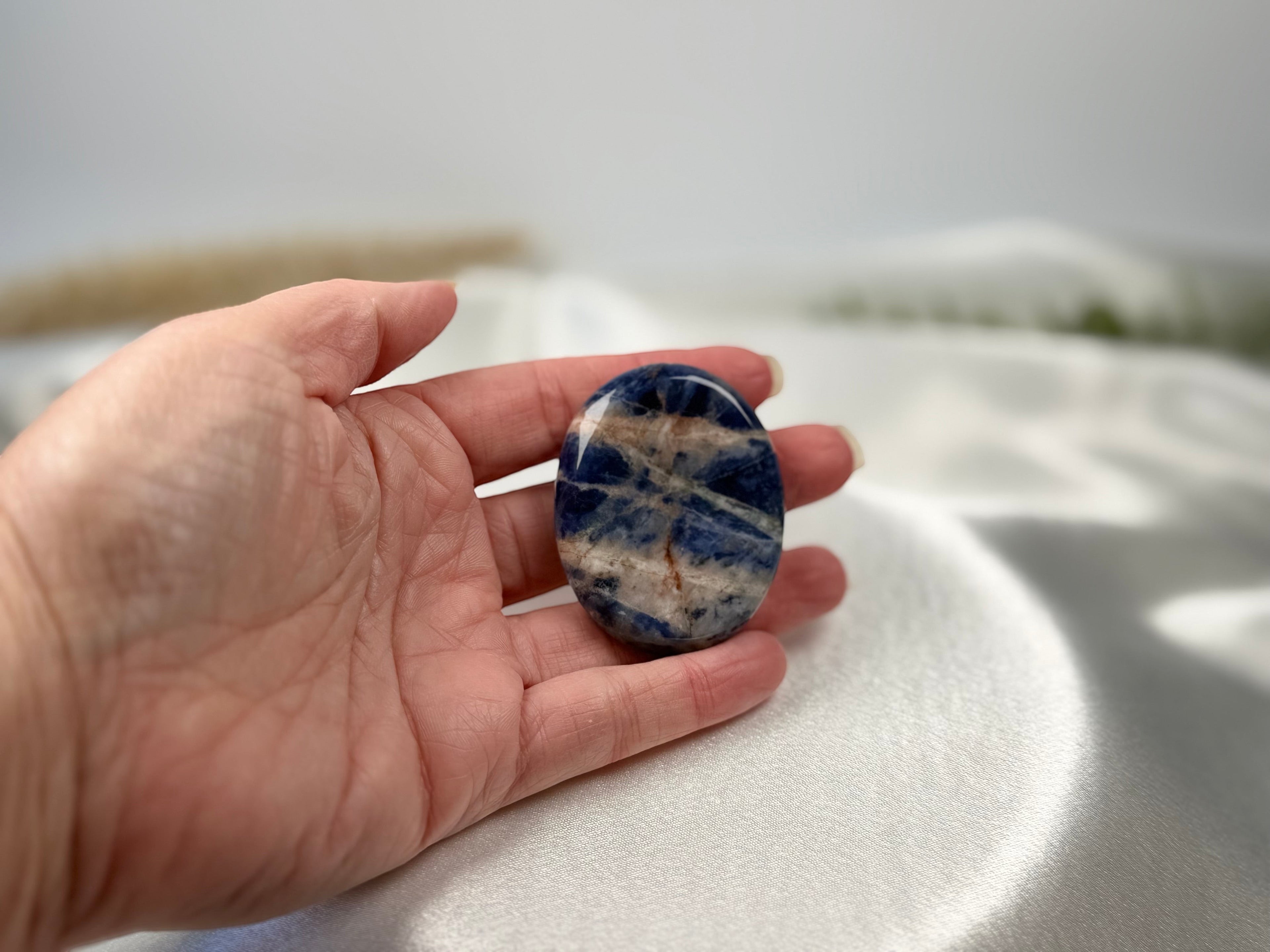 Treasured Energies Sodalite worry stone with deep blue and white patterns held in a palm for tactile grounding