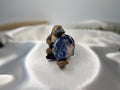 Treasured Energies blue and white Sodalite worry stone held by a small platypus figurine on a white satin fabric