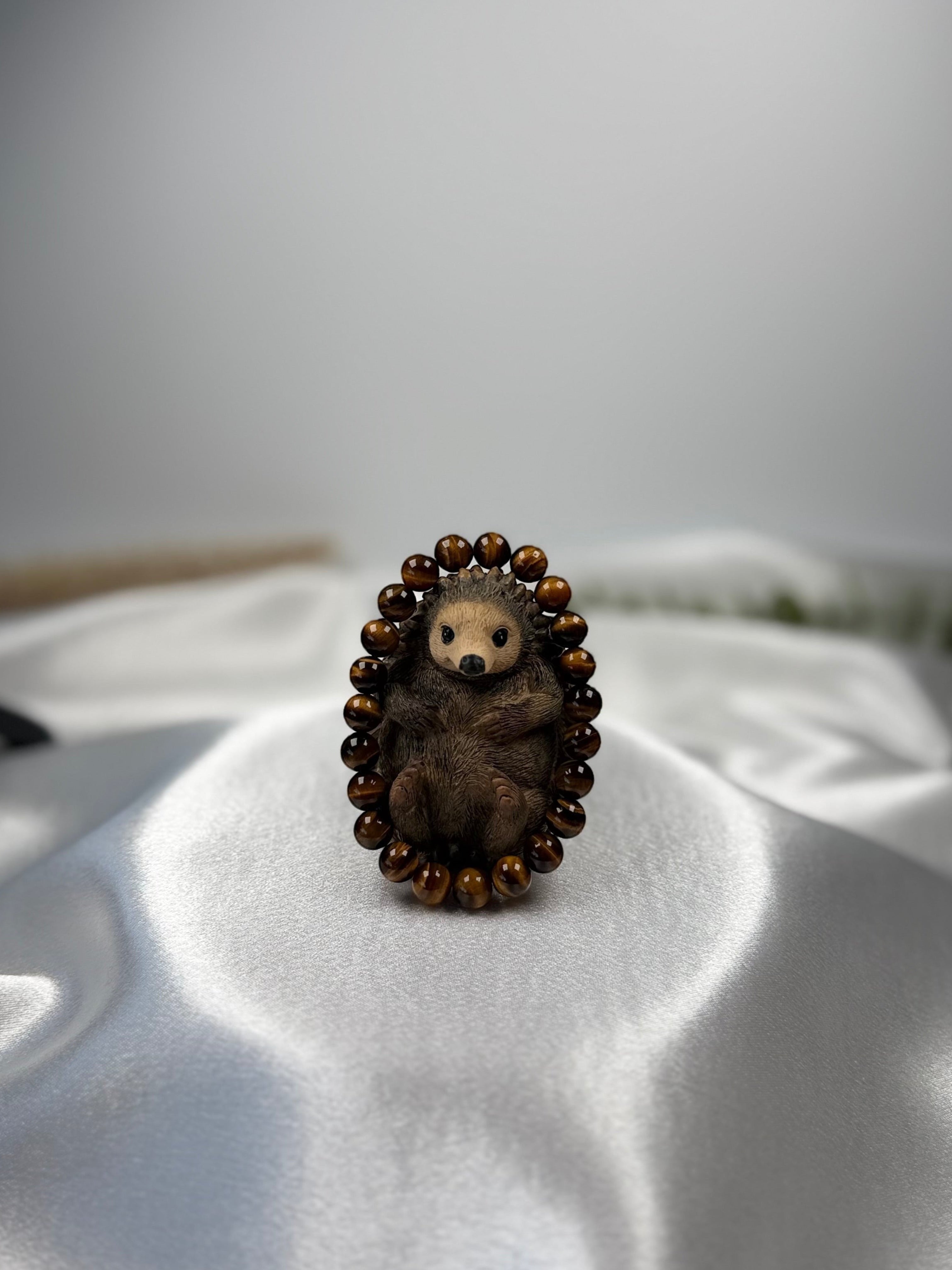Treasured Energies gold tiger eye crystal beaded bracelet featuring a cute carved hedgehog figurine on white silk