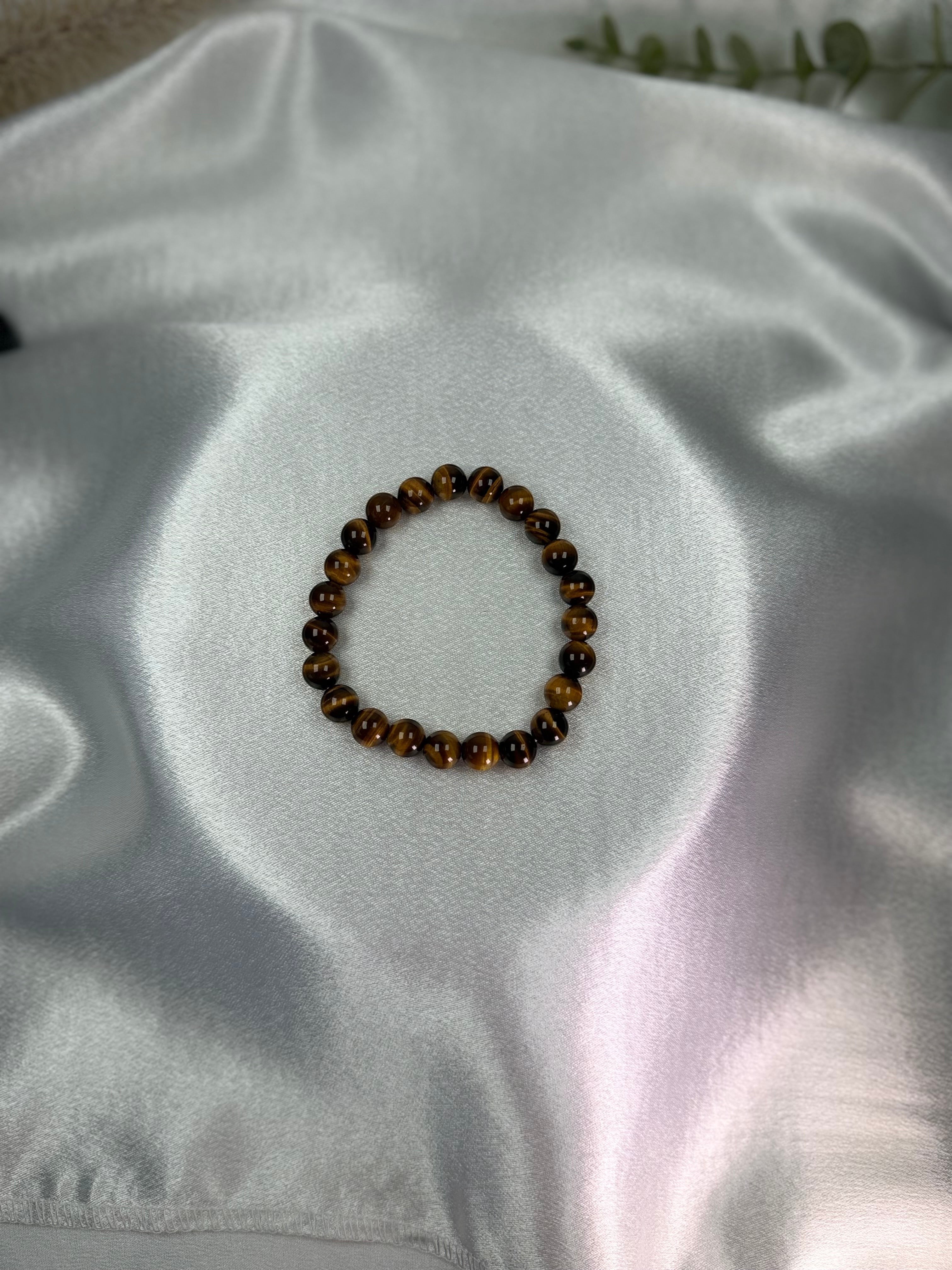 Treasured Energies gold tiger eye crystal bead bracelet on a soft white satin background