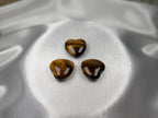 Three polished heart-shaped Tiger Eye crystals with golden-brown chatoyant bands from Treasured Energies