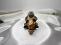 Treasured Energies polished Tigers Eye crystal heart held by a small platypus figurine on a white satin background.