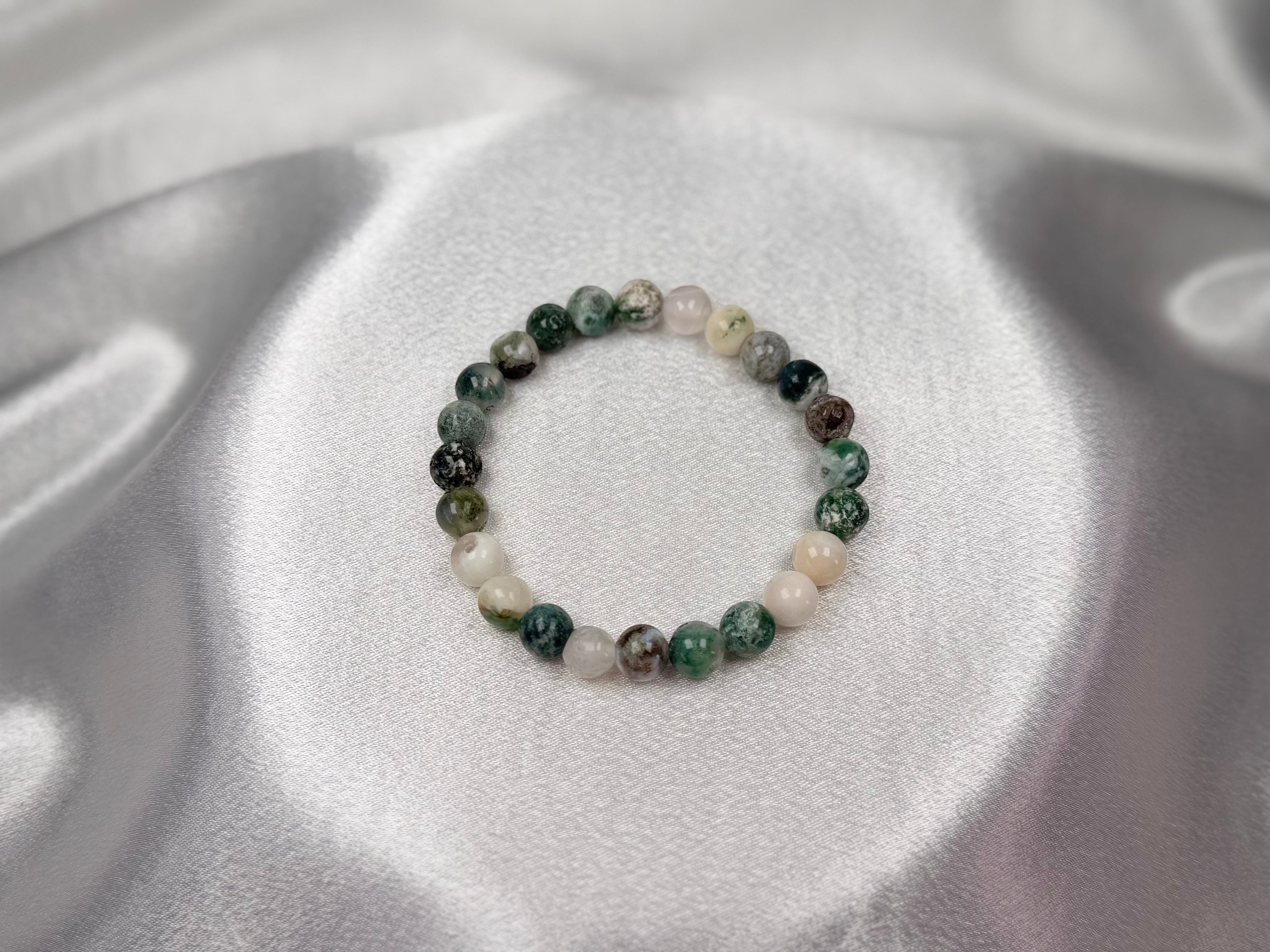 Treasured Energies tree agate crystal bead bracelet on a shimmering silver satin background