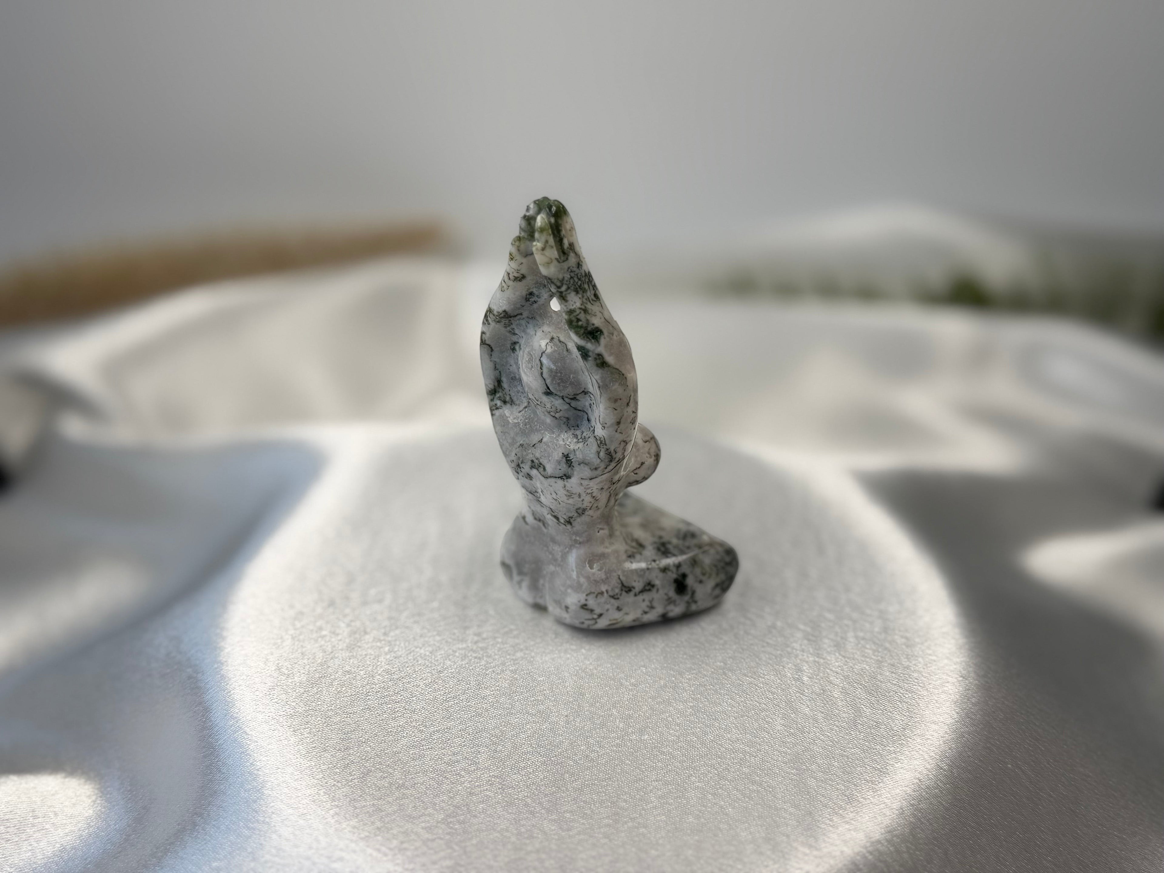 Treasured Energies tree agate yoga woman carving with white and green dendritic patterns on a white satin background.