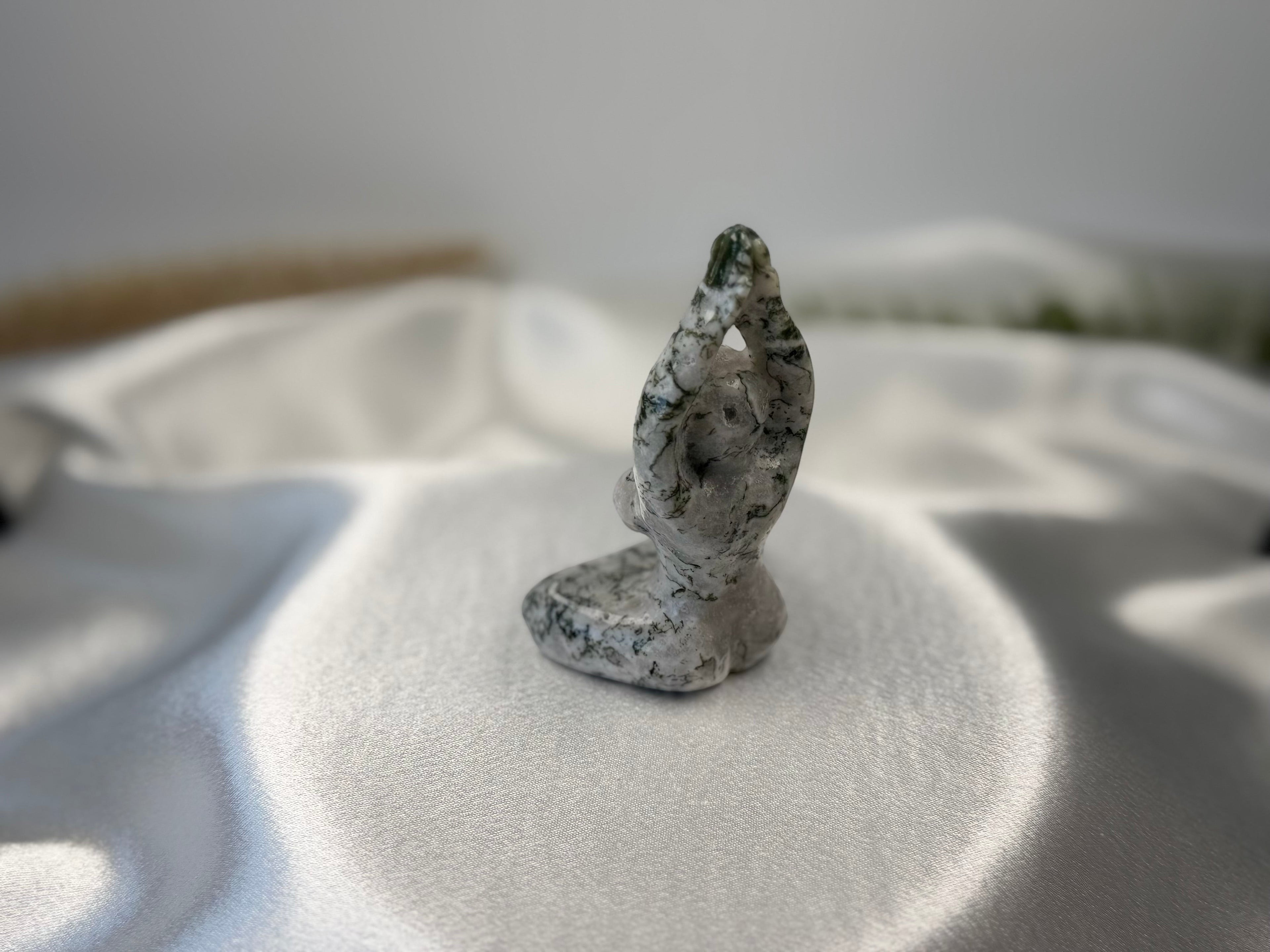 Treasured Energies Tree Agate carving of a woman in a yoga pose with white and green dendritic patterns.