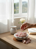 Treasured Energies tumbled rose quartz crystals in a marble bowl on a sunlit desk with a diffuser and white rose
