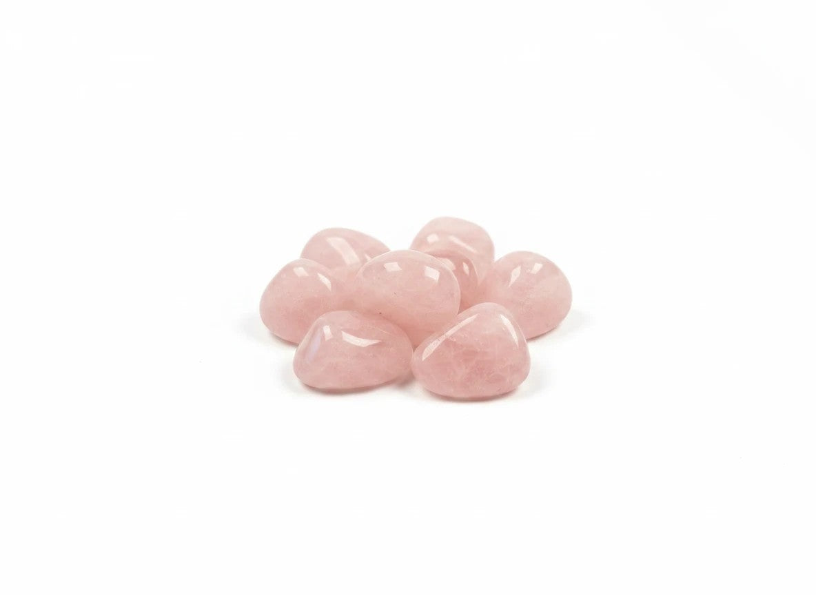 Treasured Energies tumbled rose quartz crystals with a smooth, polished light pink finish on a white background.