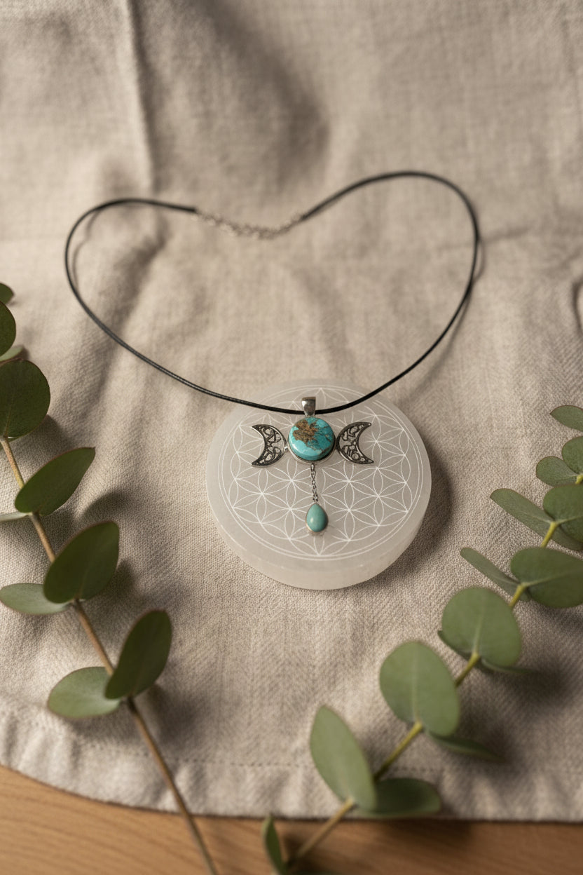 Treasured Energies turquoise triple moon goddess pendant necklace on a white selenite charging plate