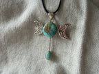 Treasured Energies turquoise triple moon goddess pendant necklace with a silver filigree design on a black cord