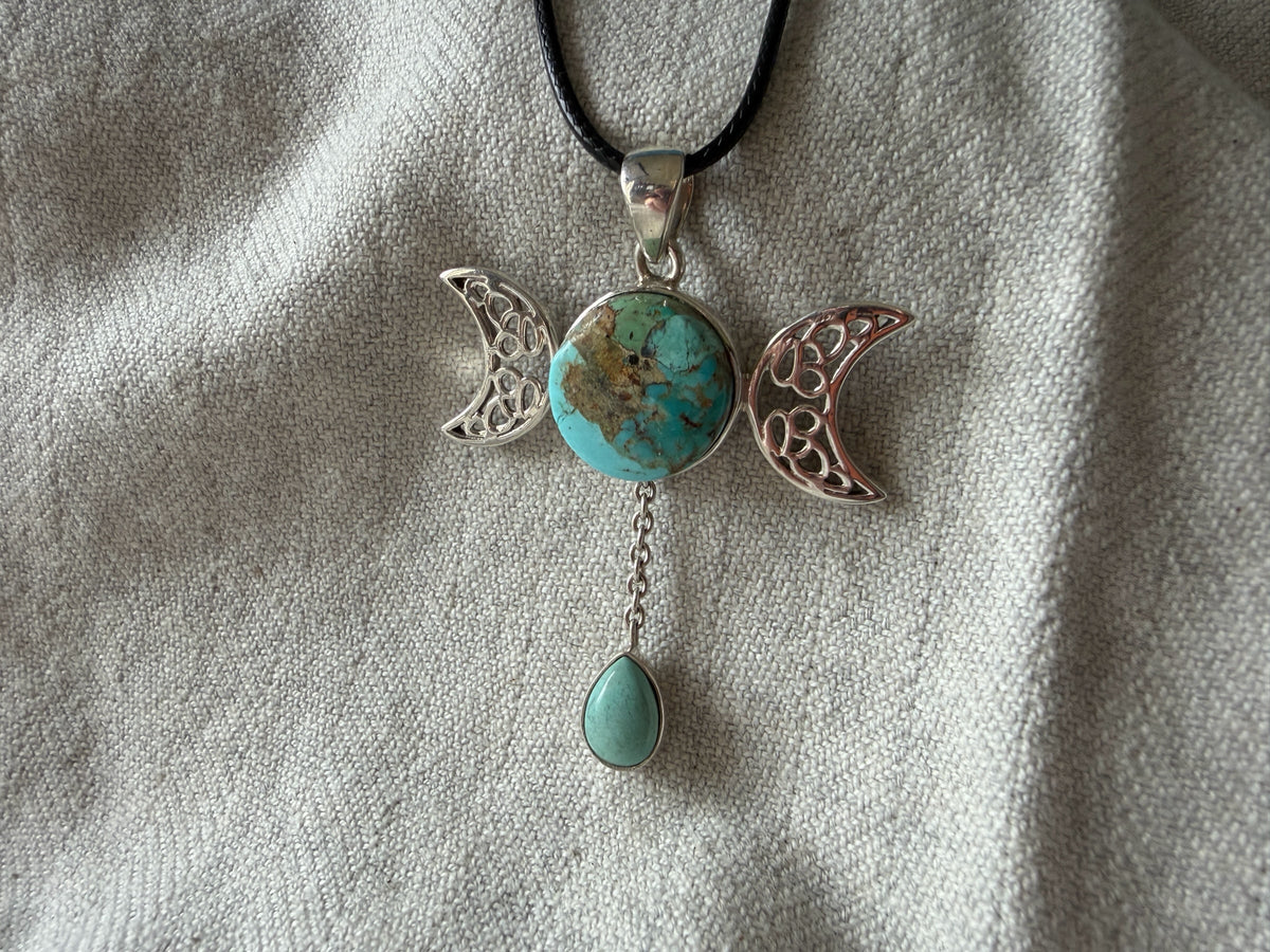 Treasured Energies turquoise triple moon goddess pendant necklace with a silver filigree design on a black cord