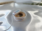 Treasured Energies small round wooden LED lamp base with white cord and control switch on a satin fabric background